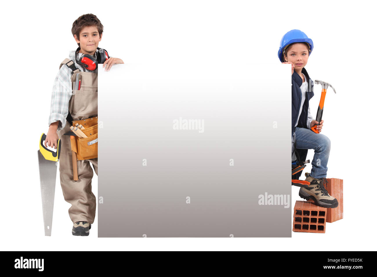 Children pretending to be construction workers standing around a blank sign Stock Photo