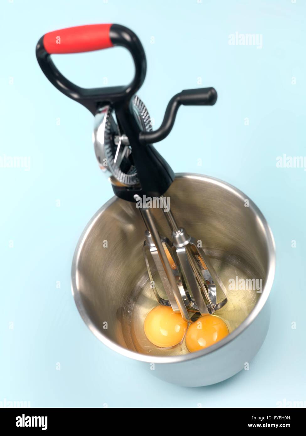 An egg beater eggs and a mixing bowl on a kitchen bench Stock Photo