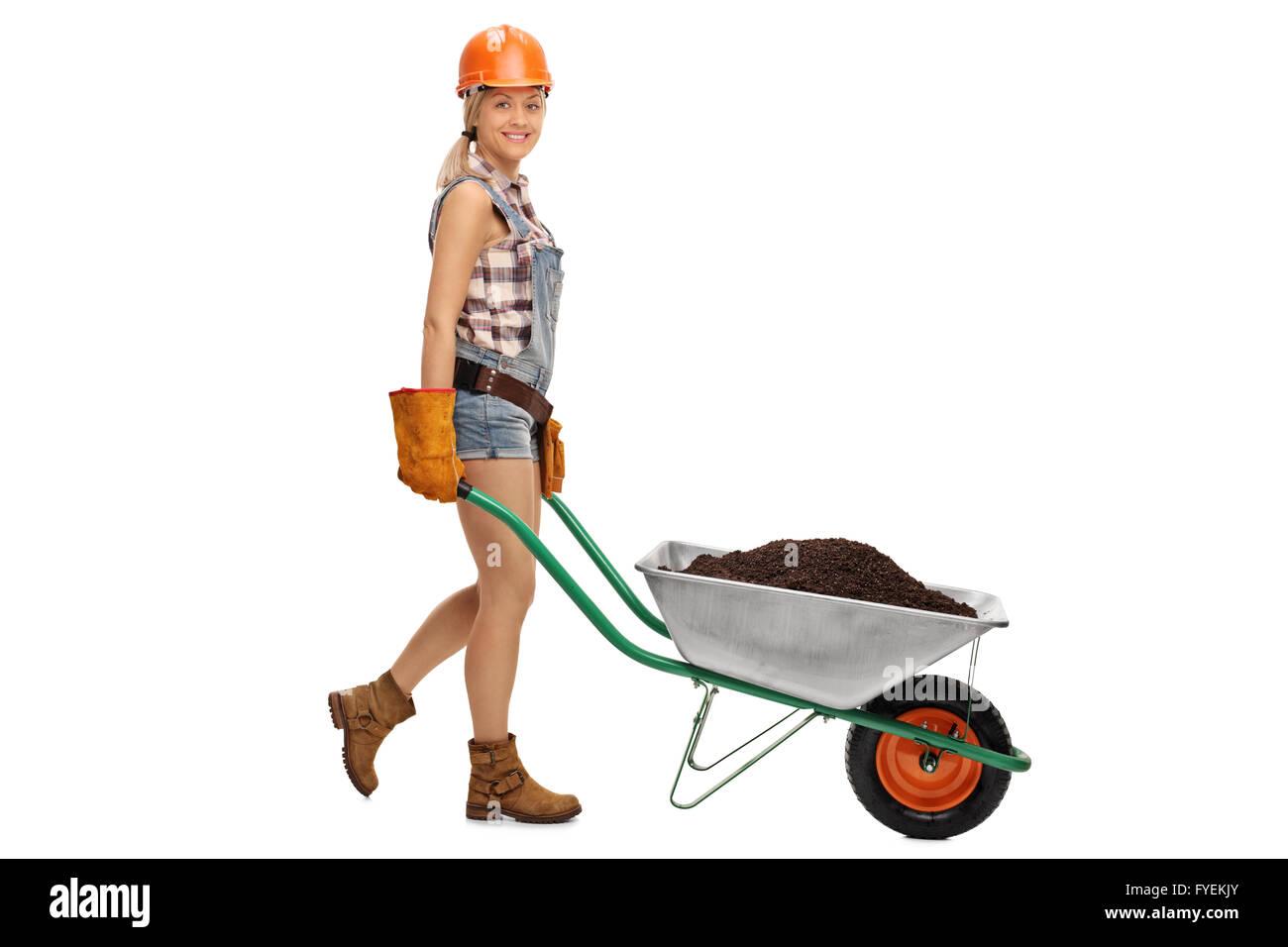 Female construction worker pushing a wheelbarrow full of dirt and ...