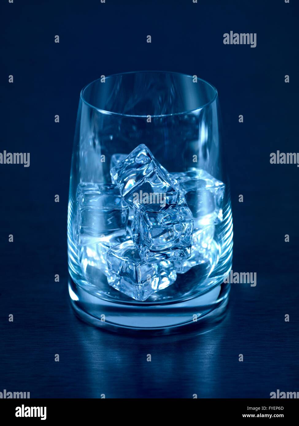 An empty glass isolated on a kitchen bench with ice cubes Stock Photo
