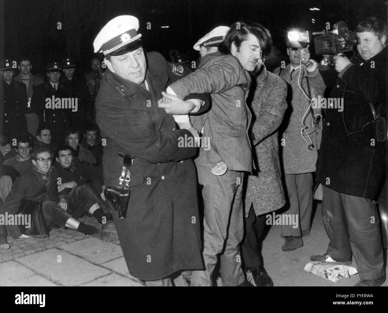 A demonstrant is arrested in front of the America House in Munich on the 8th of February in 1968. There were riots shortly before the opening of an exhibition in the course of protests against Vietnam War. Stock Photo