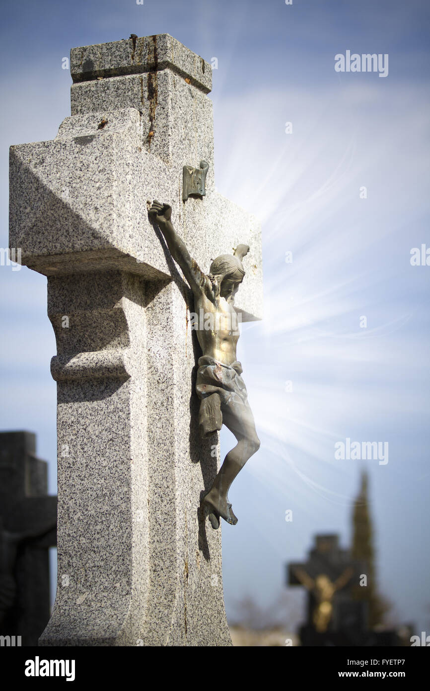Jesus Christ on stone cross, cemetery scene with mystic rays of light Stock Photo