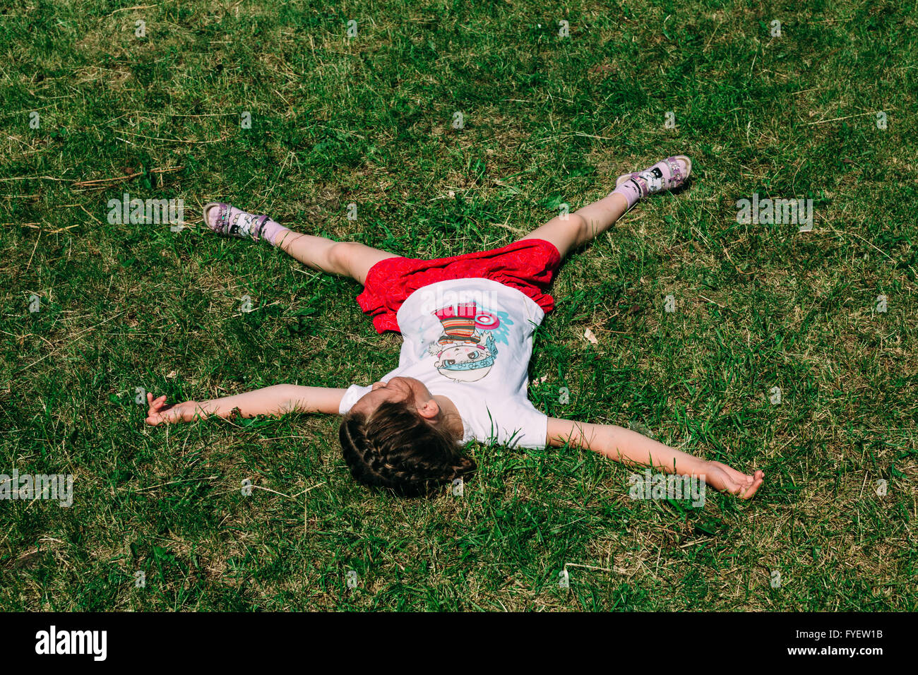 Person lies in a star pose on a grass. Stock Photo