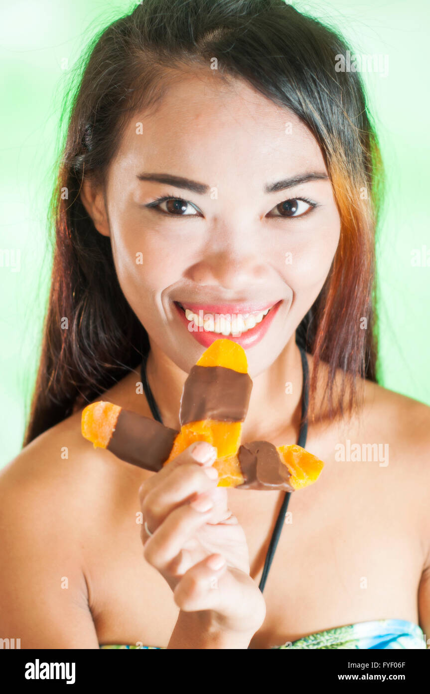 Young slim Asian woman with mango chocolate bar Stock Photo