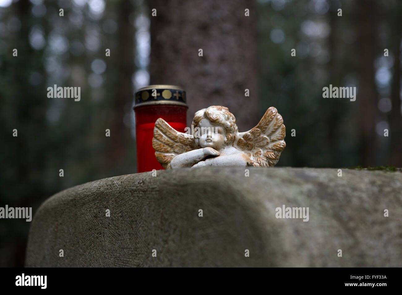 Stone angel at a grave with candle Stock Photo