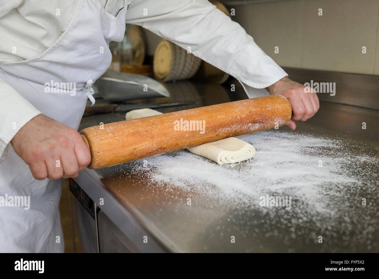 pastry chef prepares the dough with a wooden roller Stock Photo
