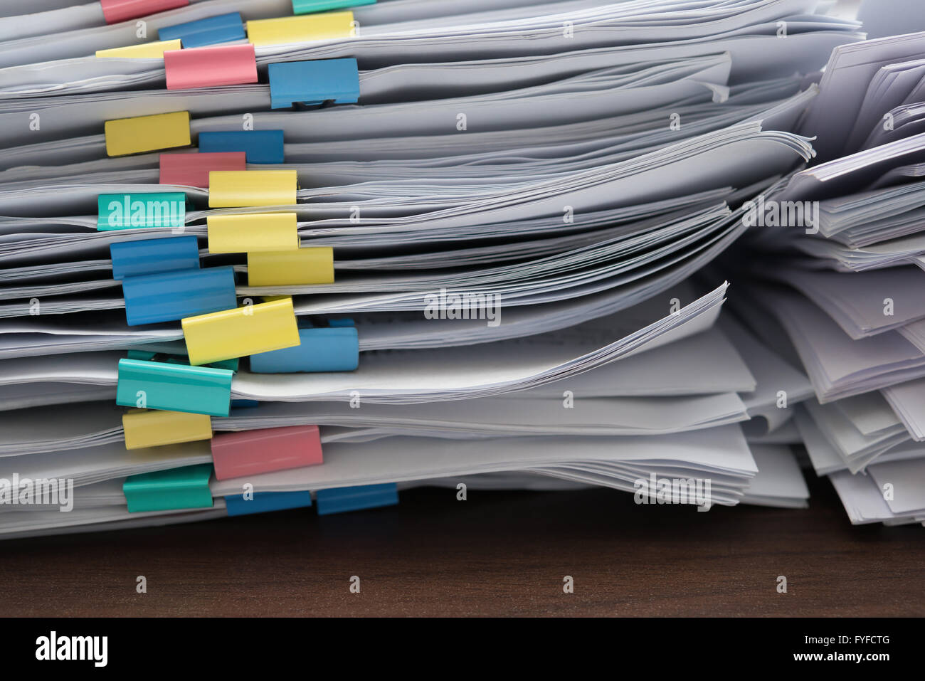 two piles of documents with colorful clips on desk stack up Stock Photo