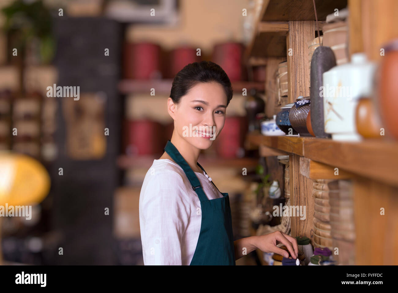 Tea house owner arranging shelf Stock Photo - Alamy