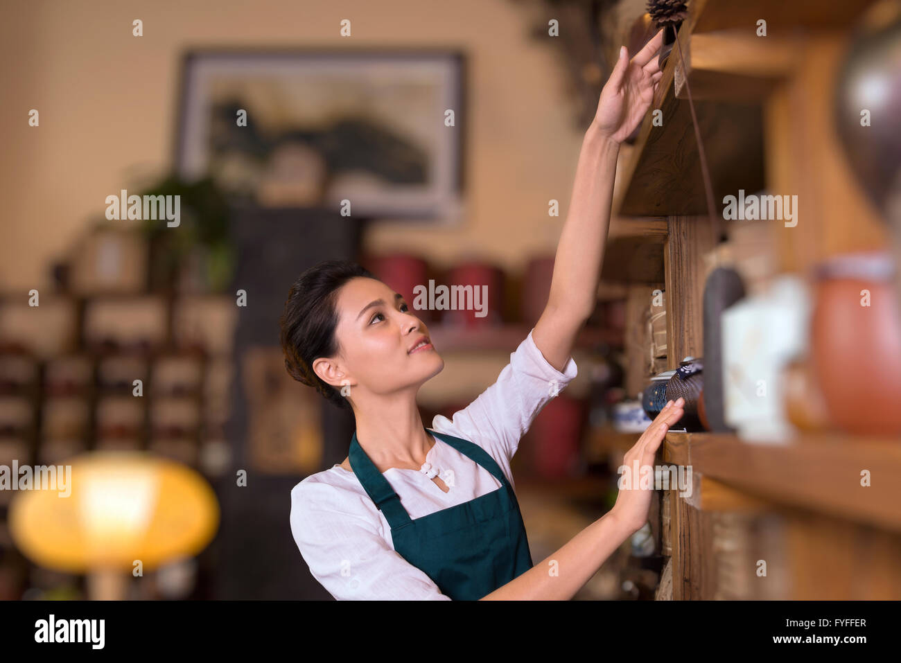 Tea house owner arranging shelf Stock Photo - Alamy