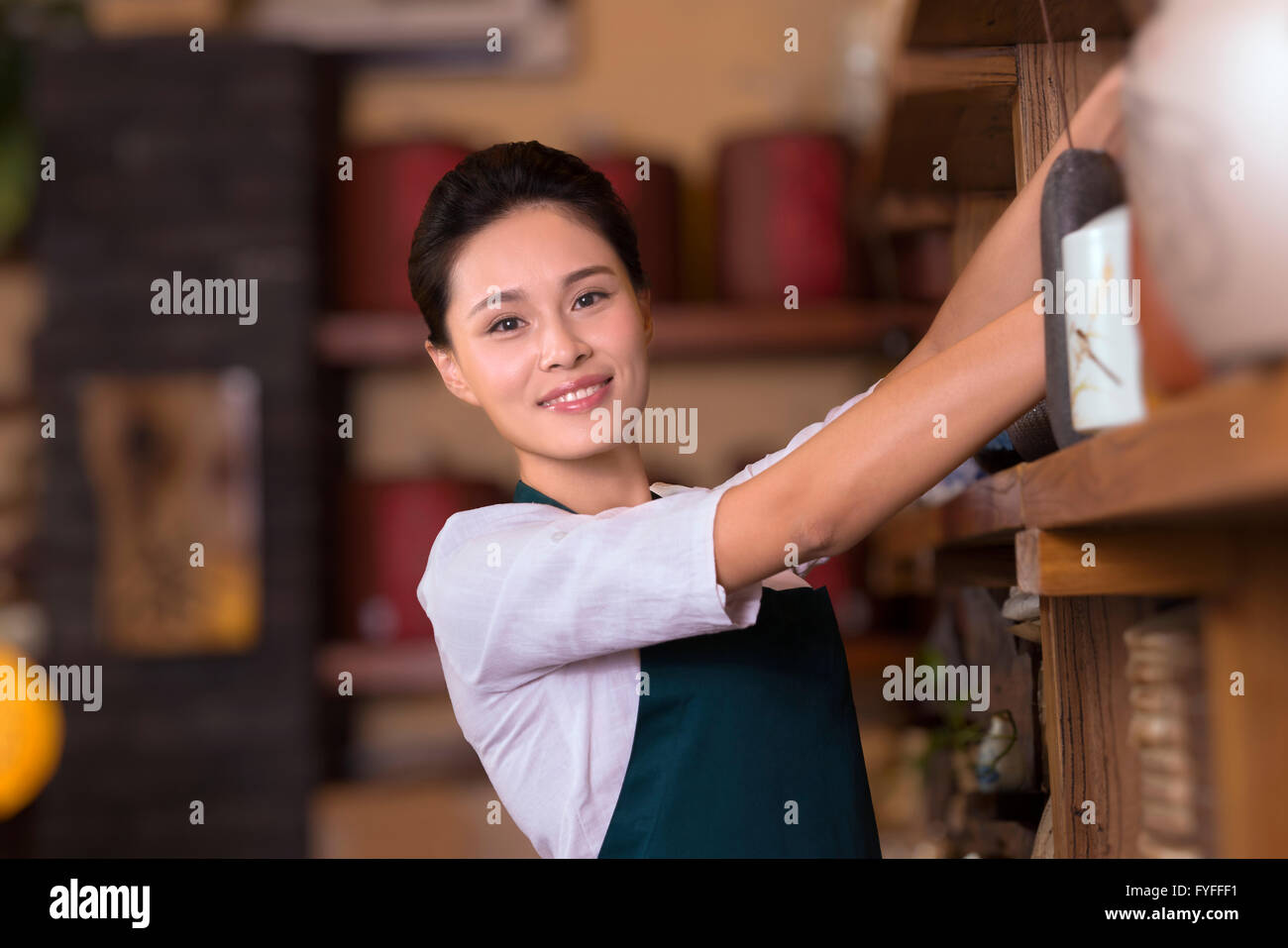 Tea house owner arranging shelf Stock Photo - Alamy