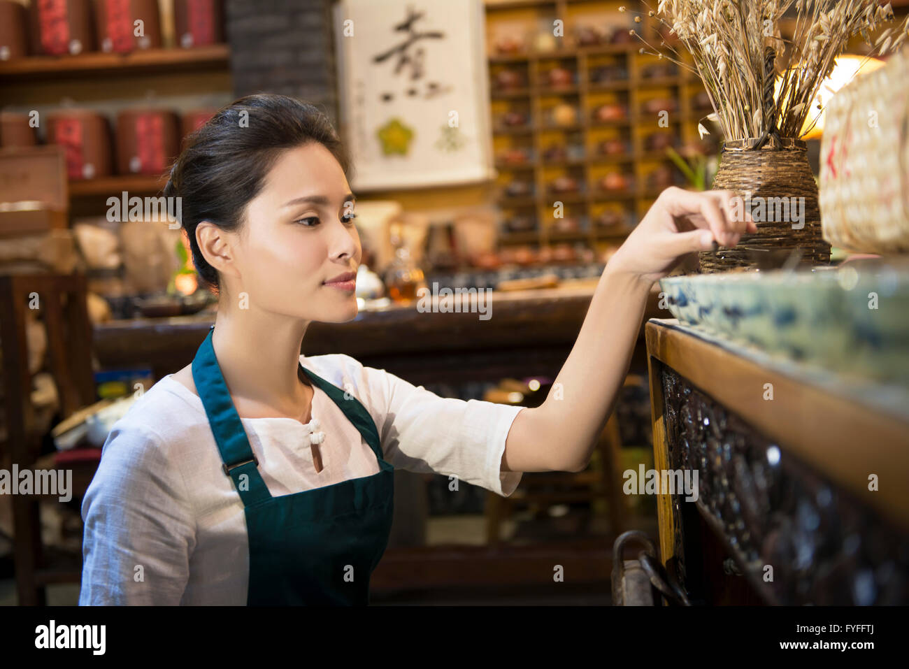 Tea house owner arranging shelf Stock Photo - Alamy