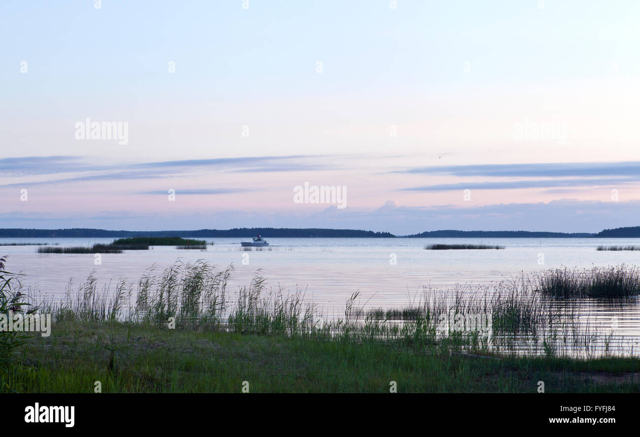 Nordic night by the Baltic Sea, Gulf of Bothnia. View, outlook of an inlet in the coastal area. Evening lit. Small boat arrive. Stock Photo