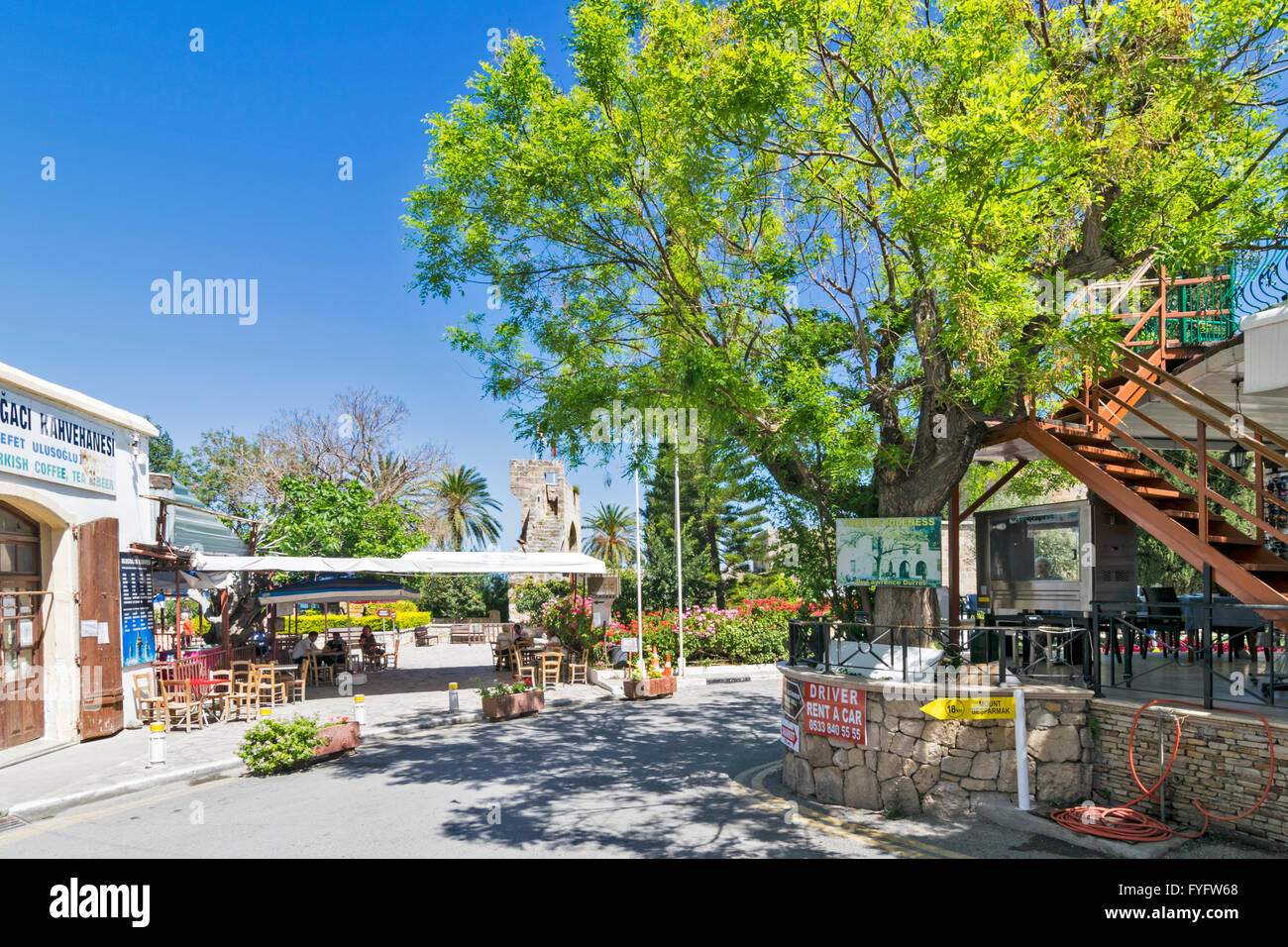 NORTH CYPRUS BELLAPAIS MAIN SQUARE LOOKING PAST LAWRENCE DURRELLS TREE OF IDLENESS TOWARDS THE MONASTERY Stock Photo