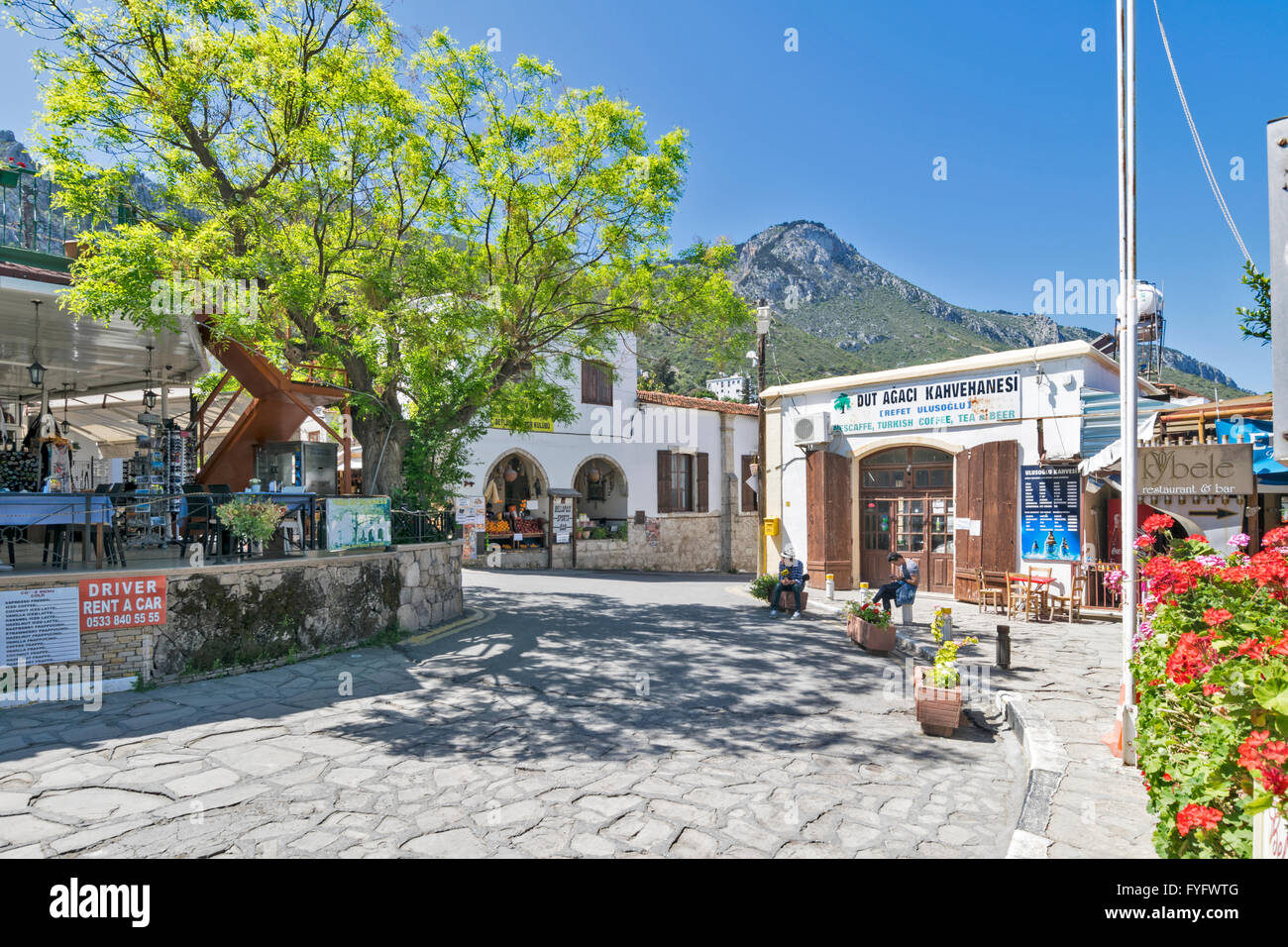 NORTH CYPRUS BELLAPAIS MAIN SQUARE WITH LAWRENCE DURRELLS TREE OF IDLENESS ALONGSIDE A RESTAURANT Stock Photo