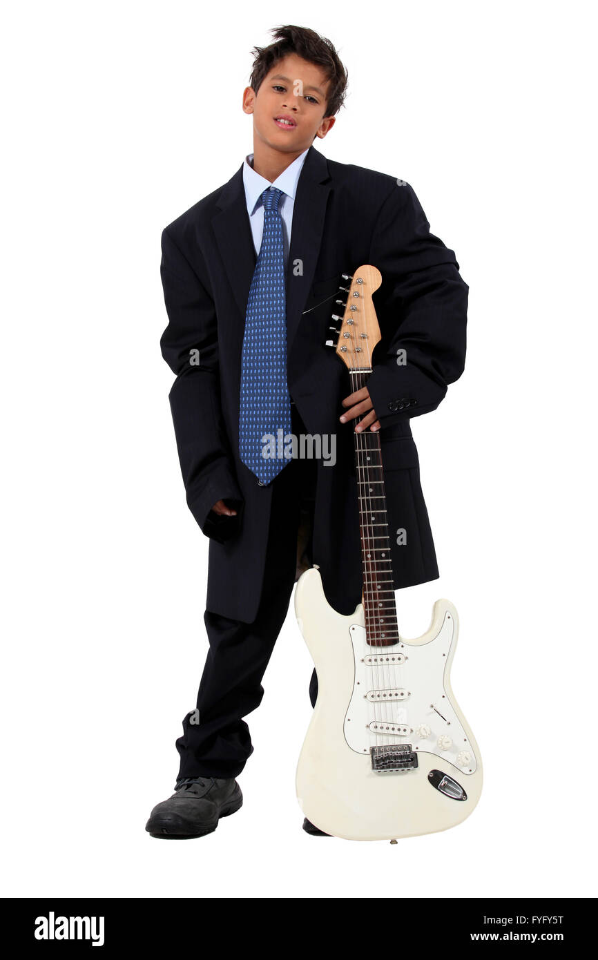 Boy in loose fitting suit stood with electric guitar Stock Photo