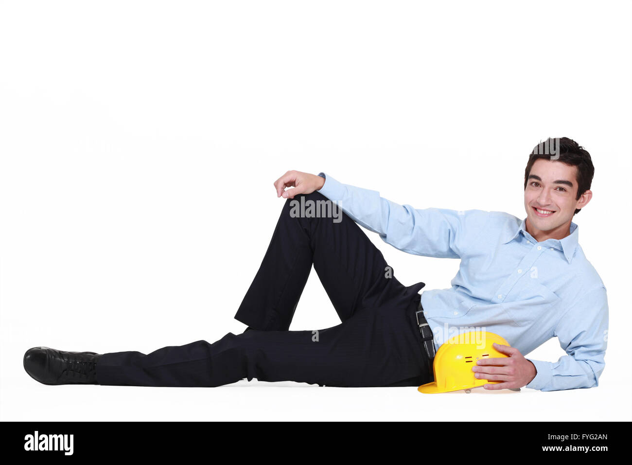 portrait of young foreman lying on floor with hard hat Stock Photo