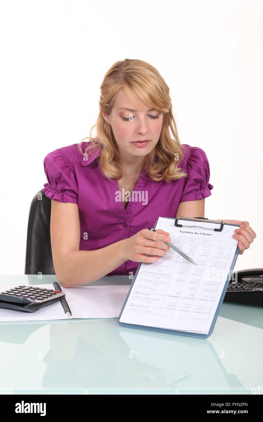 Blond office worker pointing at clip-board with pen Stock Photo