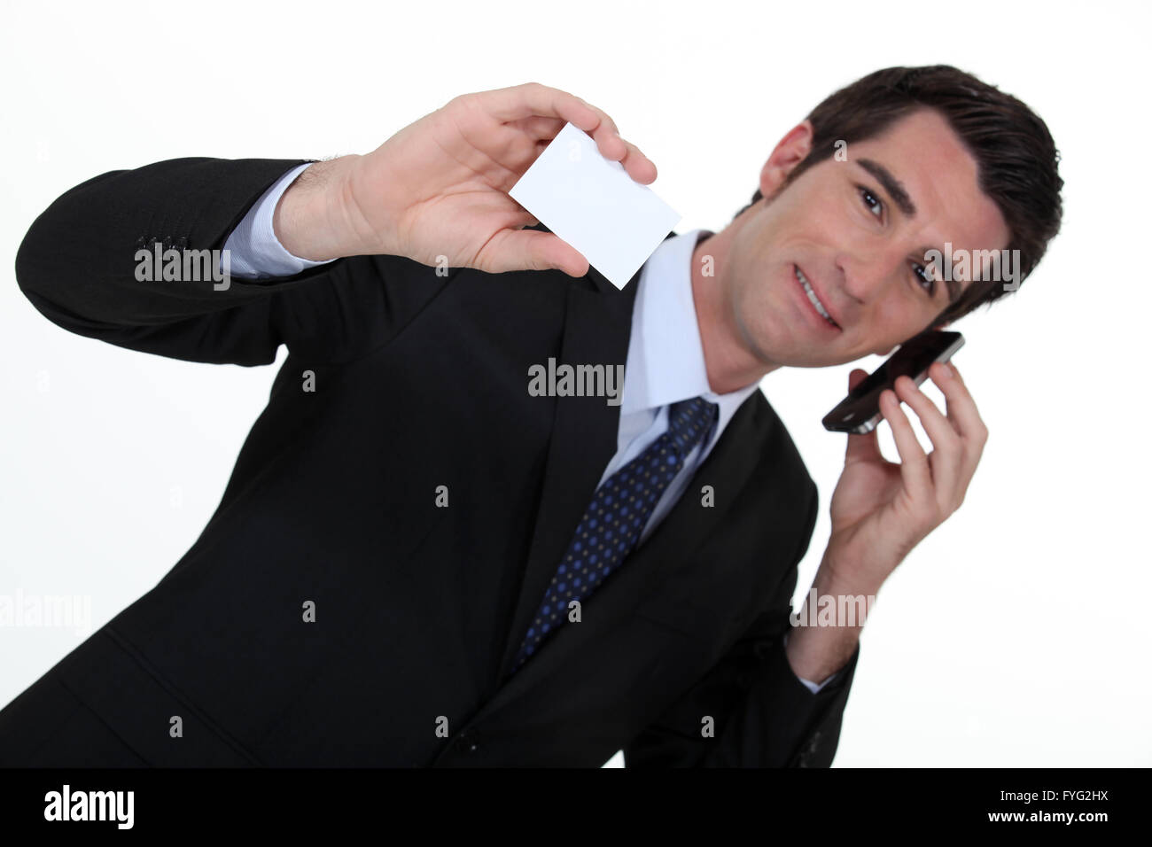 Businessman talking on his mobile phone and holding a card Stock Photo