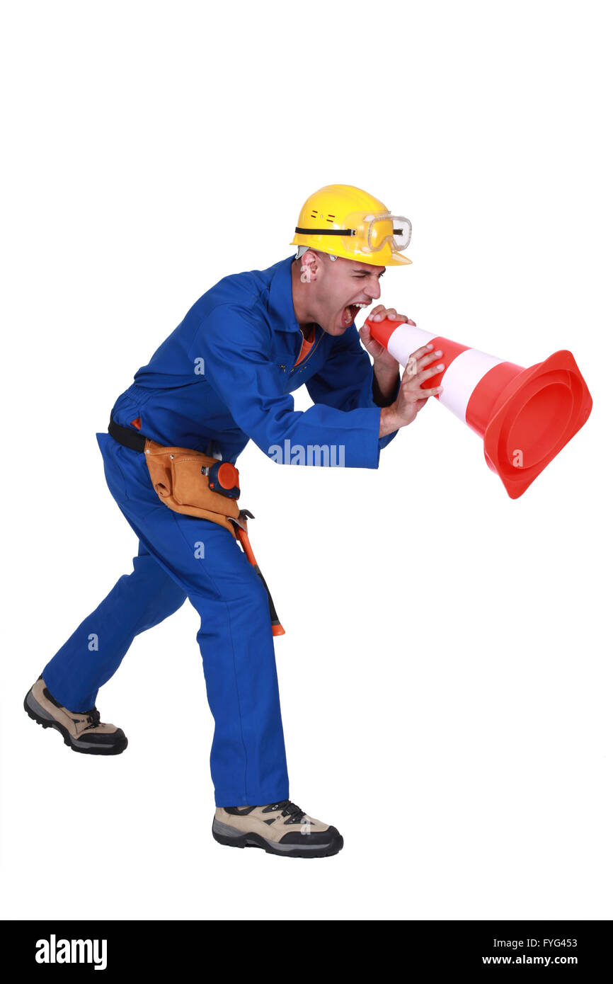 Construction worker shouting into a traffic cone Stock Photo