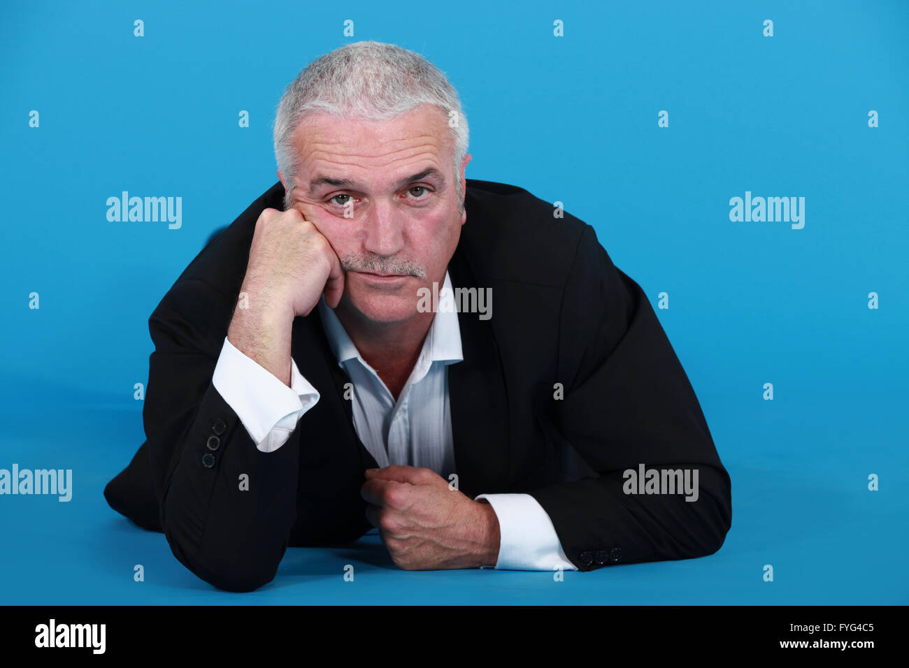 A mature bored businessman laying on the floor. Stock Photo