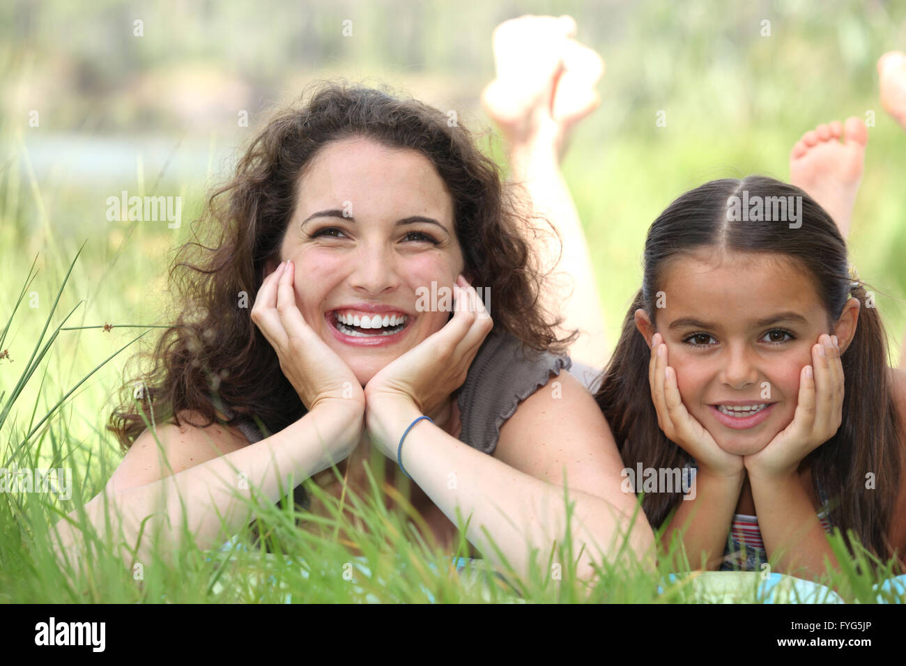 a woman and a little girl lying down in the grass Stock Photo