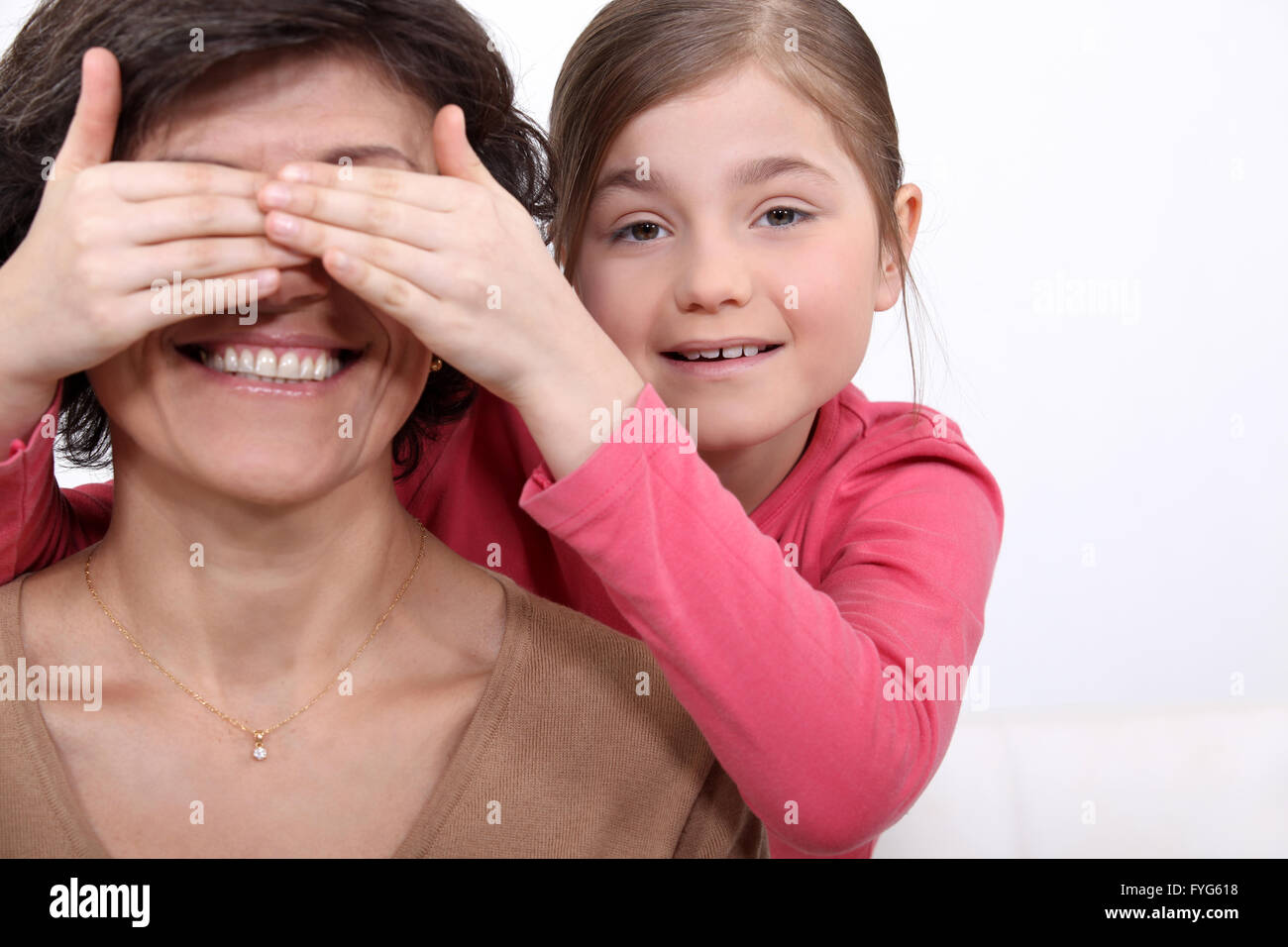 daughter putting her hands before mother's eyes Stock Photo