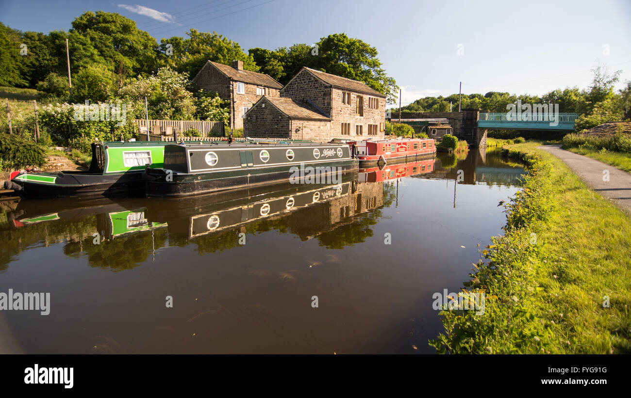 Narrowboats moored on the Leeds and Liverpool Canal beside a farmhouse in the Aire Valley. Stock Photo