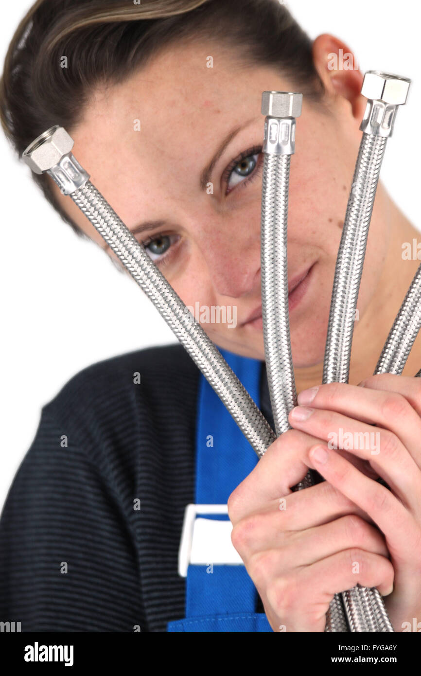 Female plumber holding selection of metal pipes Stock Photo