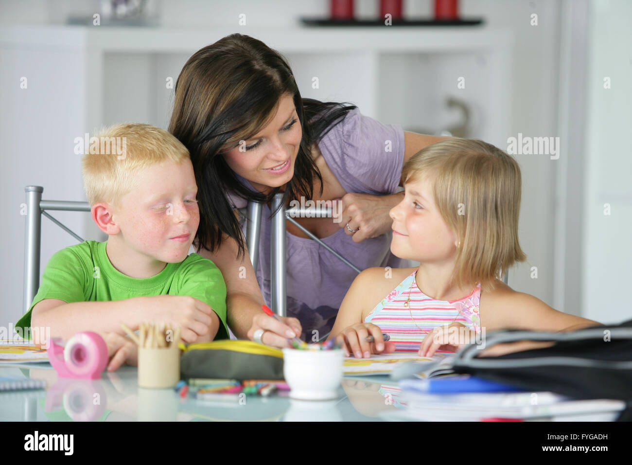 Mother watching brother and sister doing their homework Stock Photo