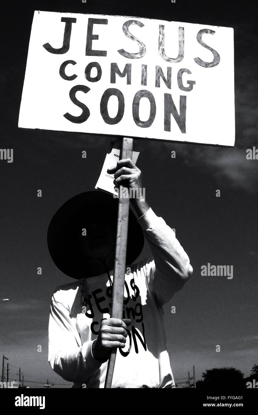 Ghostly looking man holding a sign on the street that reads 'Jesus Coming Soon' Stock Photo