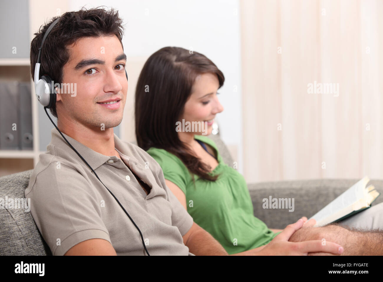 a woman reading and a young man listening music on a couch Stock Photo ...