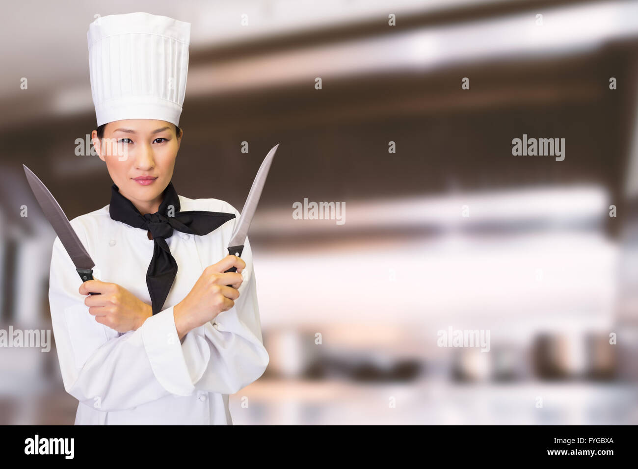 Composite image of confident female cook holding knives in kitchen Stock Photo