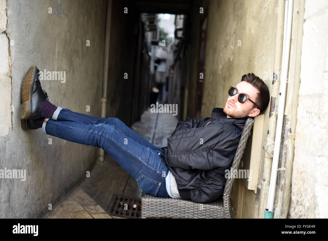 trendy young man shades sitting chair cool alley model release available Stock Photo