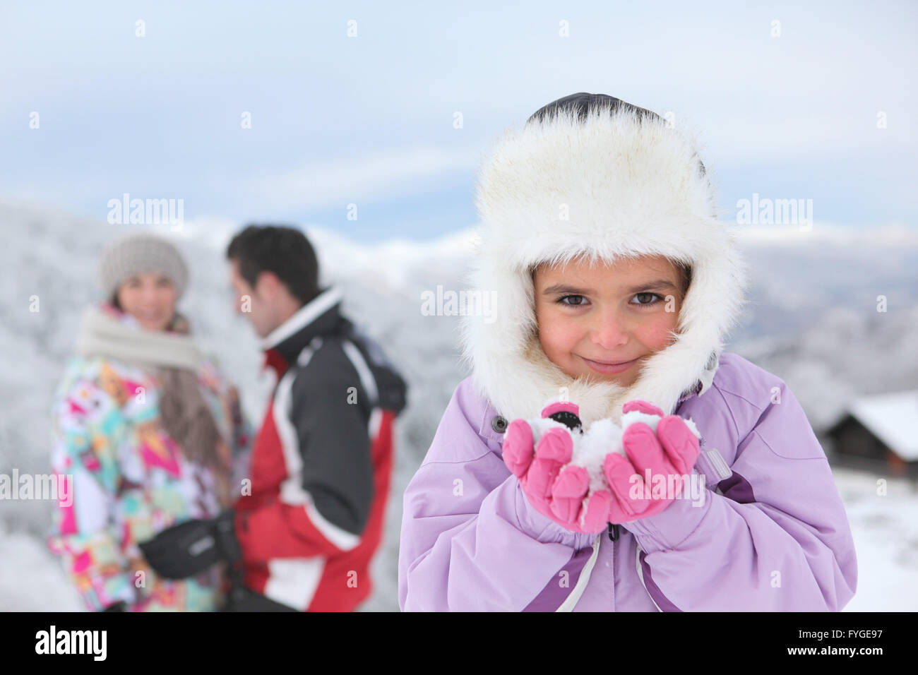 Little girl playing in the snow with her parents Stock Photo
