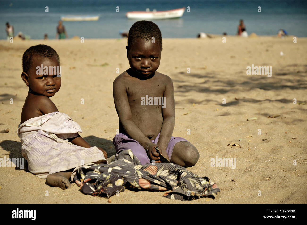 Kids sitting on the beach in the village of Chembe, Cape Maclear, Malawi Stock Photo