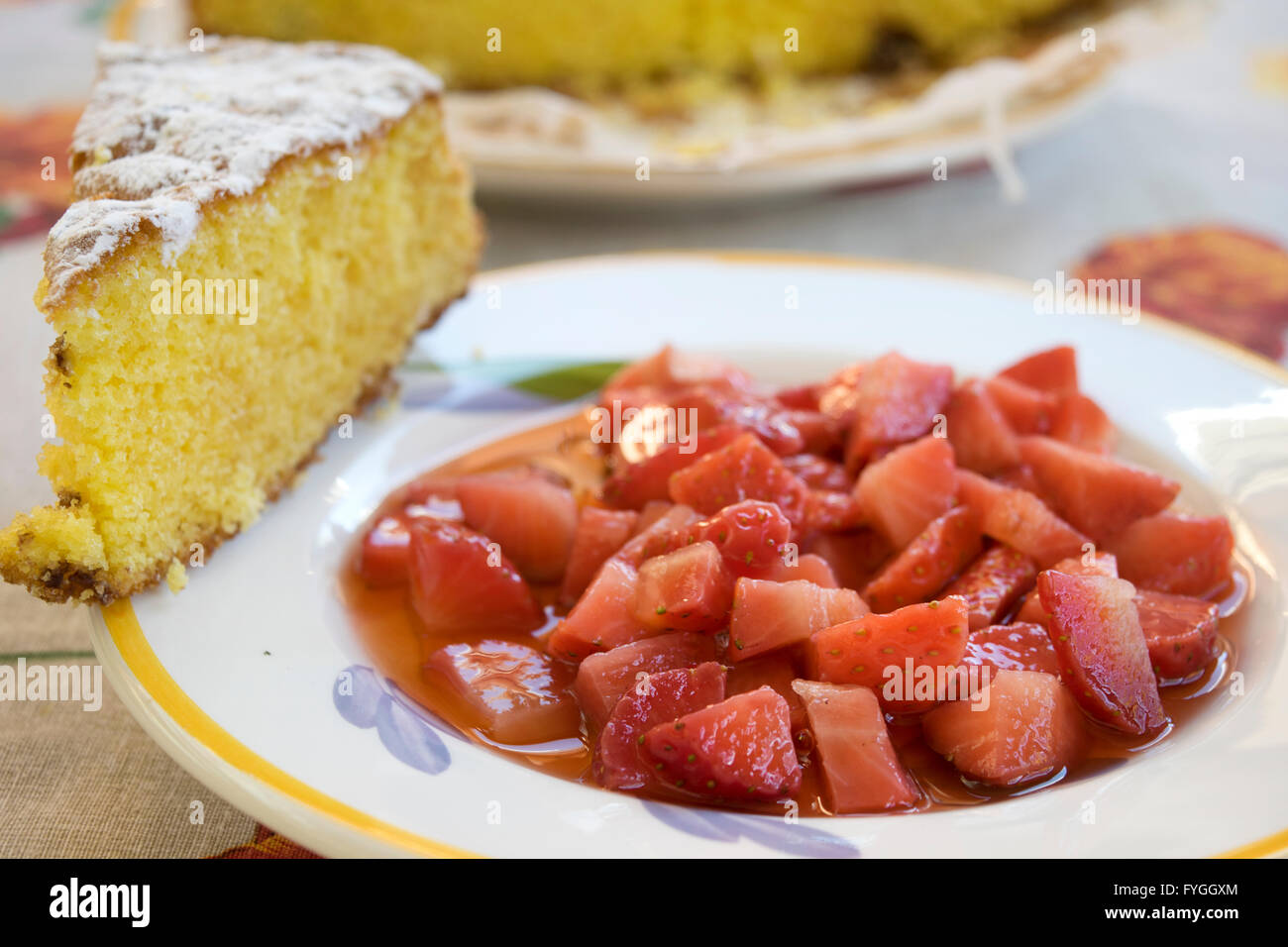 chopped strawberries in a dish with a slice of sponge cake Stock Photo