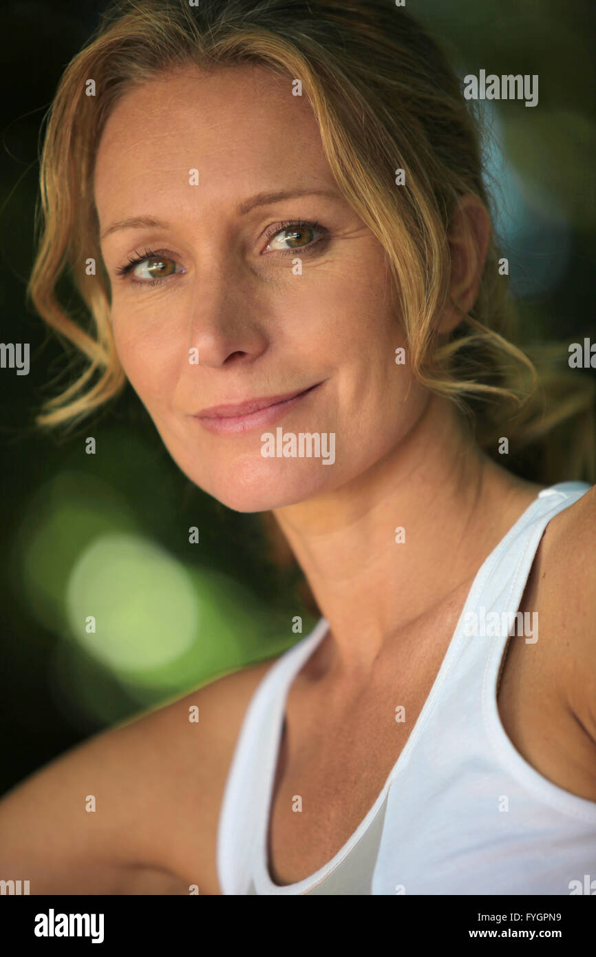 Closeup of woman in white vest in leafy environment Stock Photo
