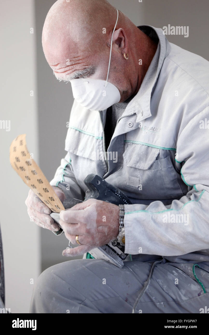 Decorator fitting sandpaper onto an electric sander Stock Photo