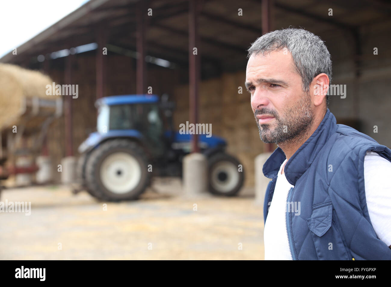 Farmer standing in front of a barn containing a tractor Stock Photo - Alamy