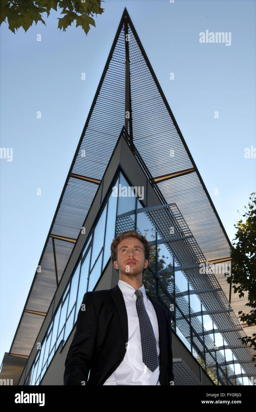 Man With Building Young man standing in front of a modern building Stock Photo - Alamy