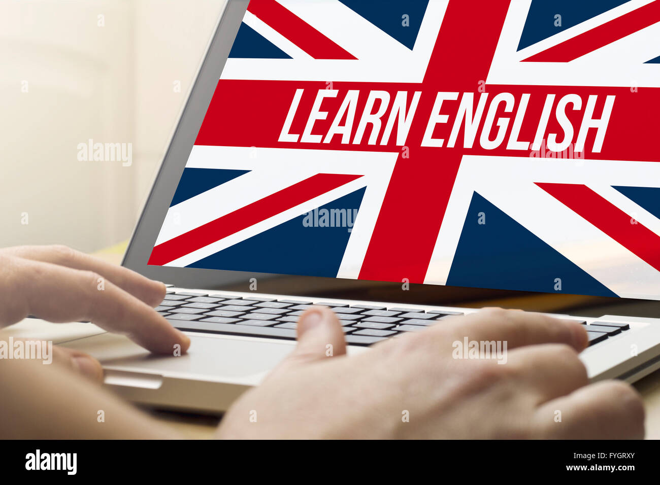 online business concept: man using a laptop with learn english on the screen. Screen graphics are made up. Stock Photo