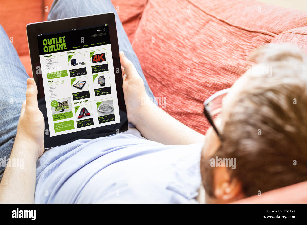 technology lifestyle concept: hipster on the sofa with online outlet shop tablet. Screen graphics are made up. Stock Photo