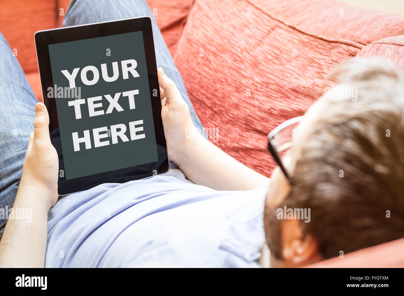 technology lifestyle business concept: hipster man with your text here on a tablet at the sofa Stock Photo