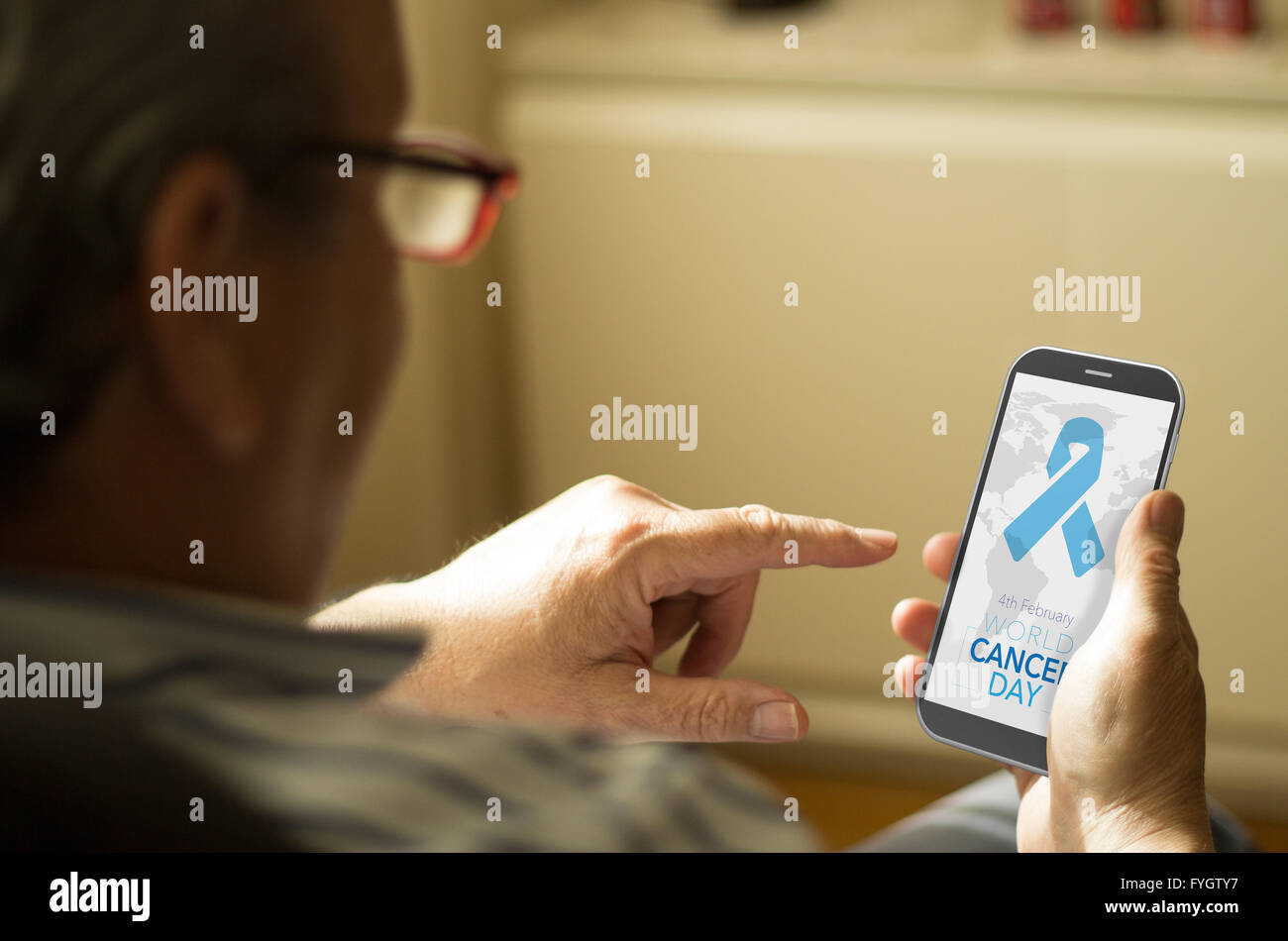business concept: man with World Cancer Day background on screen phone at home. All screen graphics are made up. Stock Photo