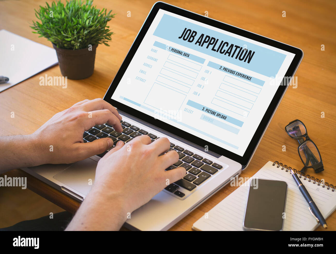 Businessman at work. Close-up top view of man working on laptop job application. All screen graphics are made up. Stock Photo