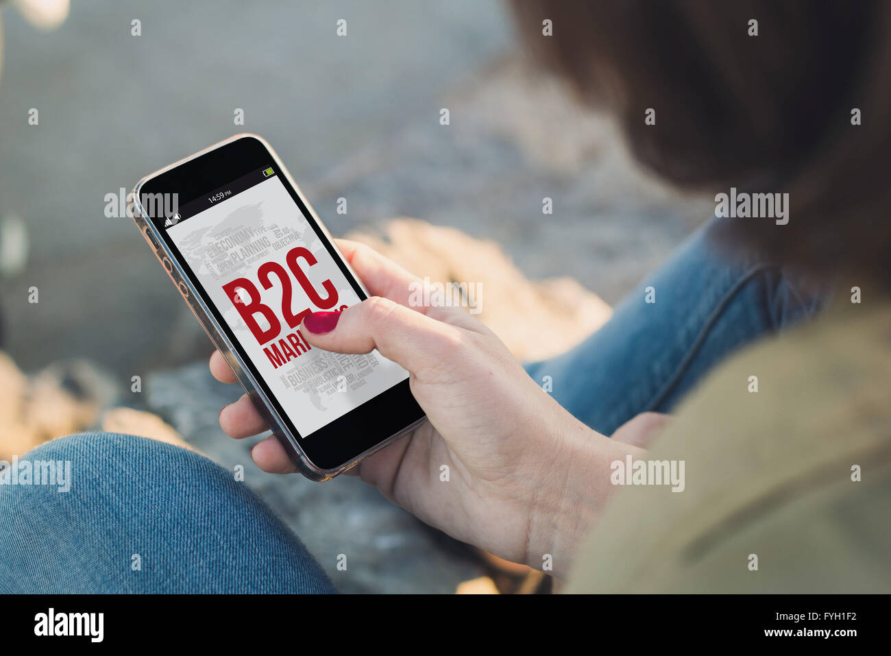 woman holding a smartphone and touching the screen shoing b2c marketing concept. All screen graphics are made up. Stock Photo
