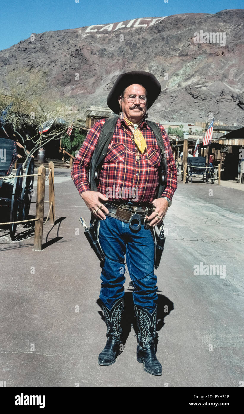 The Deputy Sheriff known as Doc Holliday strolls the streets of a “living” ghost town called Calico, a mining camp that yielded more than $20 million worth of silver during the late 1800s in Southern California, USA. Lawmen toted their six-guns in this rough-and-tough community that once boasted 3,500 residents and 22 saloons. Calico became deserted after the silver ore ran out and it wasn't until 1951 that historical restoration of this Old West town began. Today Calico Ghost Town is a San Bernardino County park that has become a major tourist attraction. Stock Photo