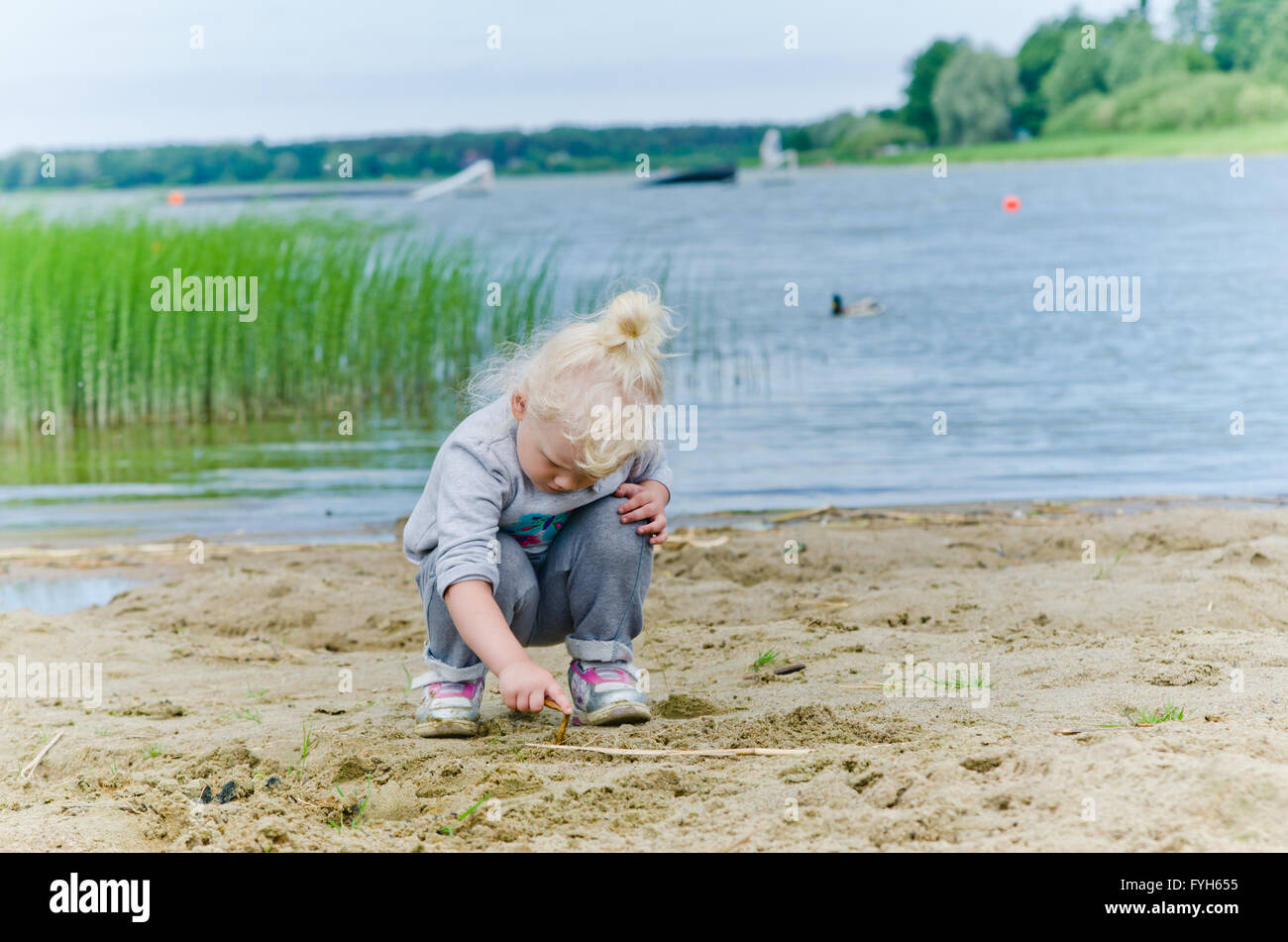 Girl playing in the sand on the shore of Lake Stock Photo - Alamy