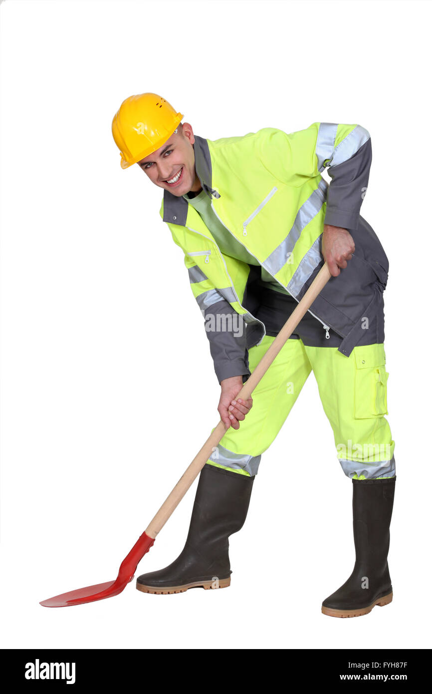 bricklayer all smiles with shovel against studio background Stock Photo
