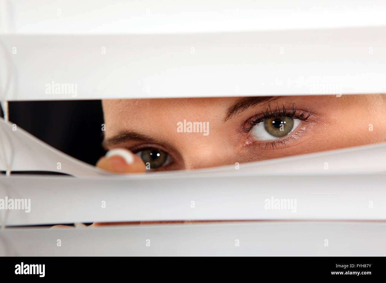 Closeup of a woman's eyes spying through blinds Stock Photo Alamy